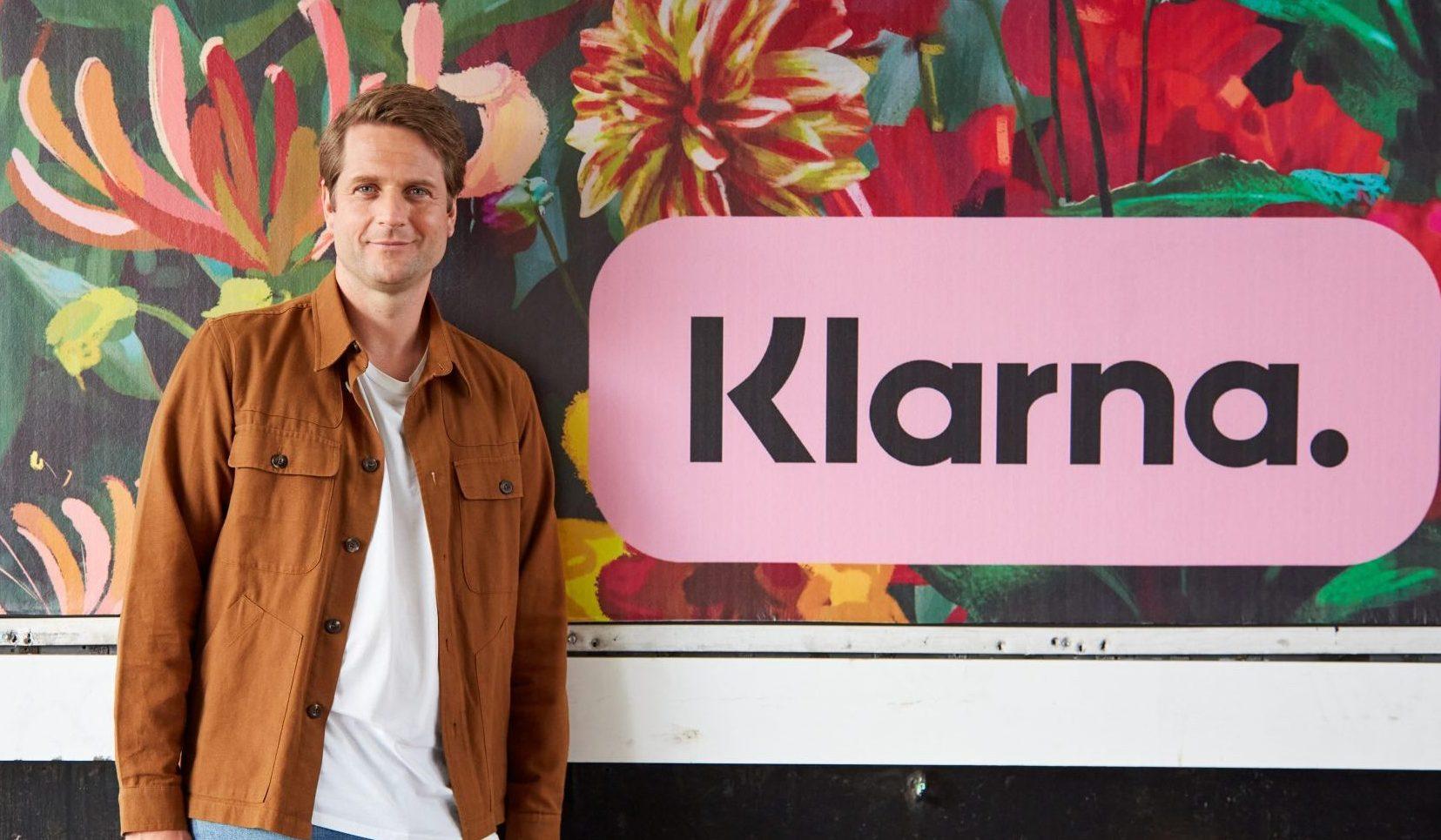 An image of Sebastian Siemiatkowski, CEO of Klarna, standing next to a Klarna sign.