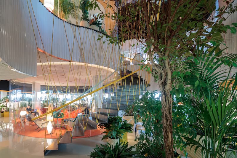 A curved staircase and plenty of plants inside coworking space Second Home Spitalfields