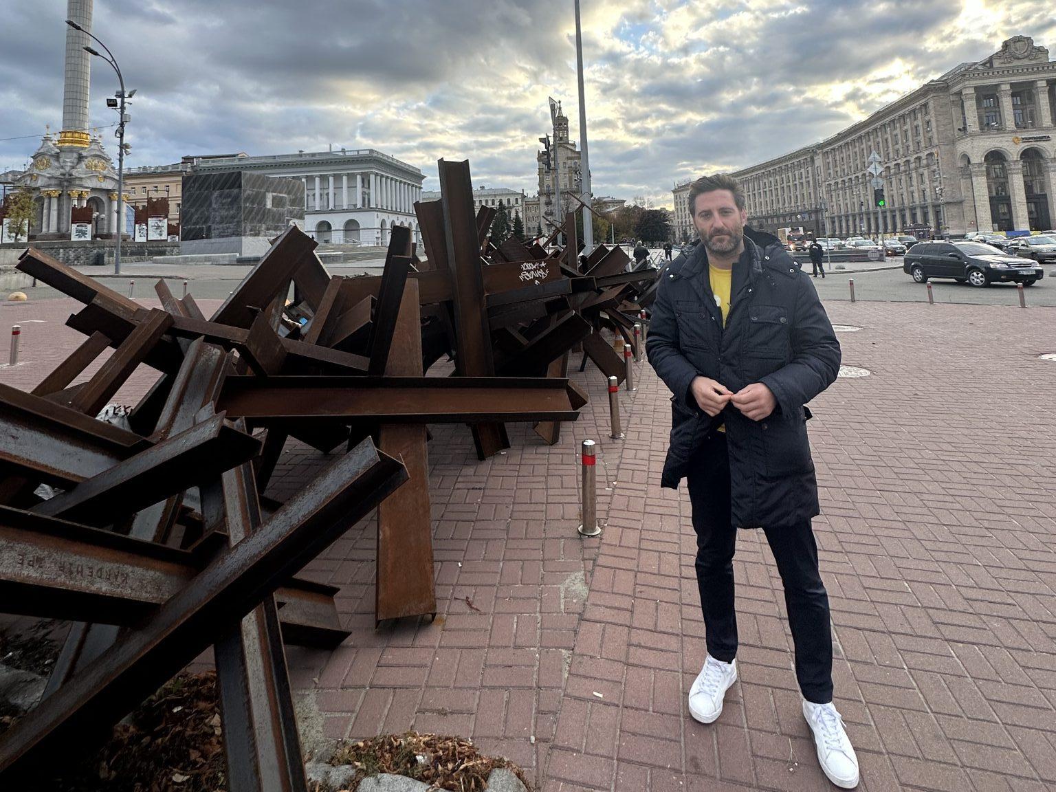 An image of Daniel Korski in Ukraine, standing in a city square next to some shoulder-high tank traps