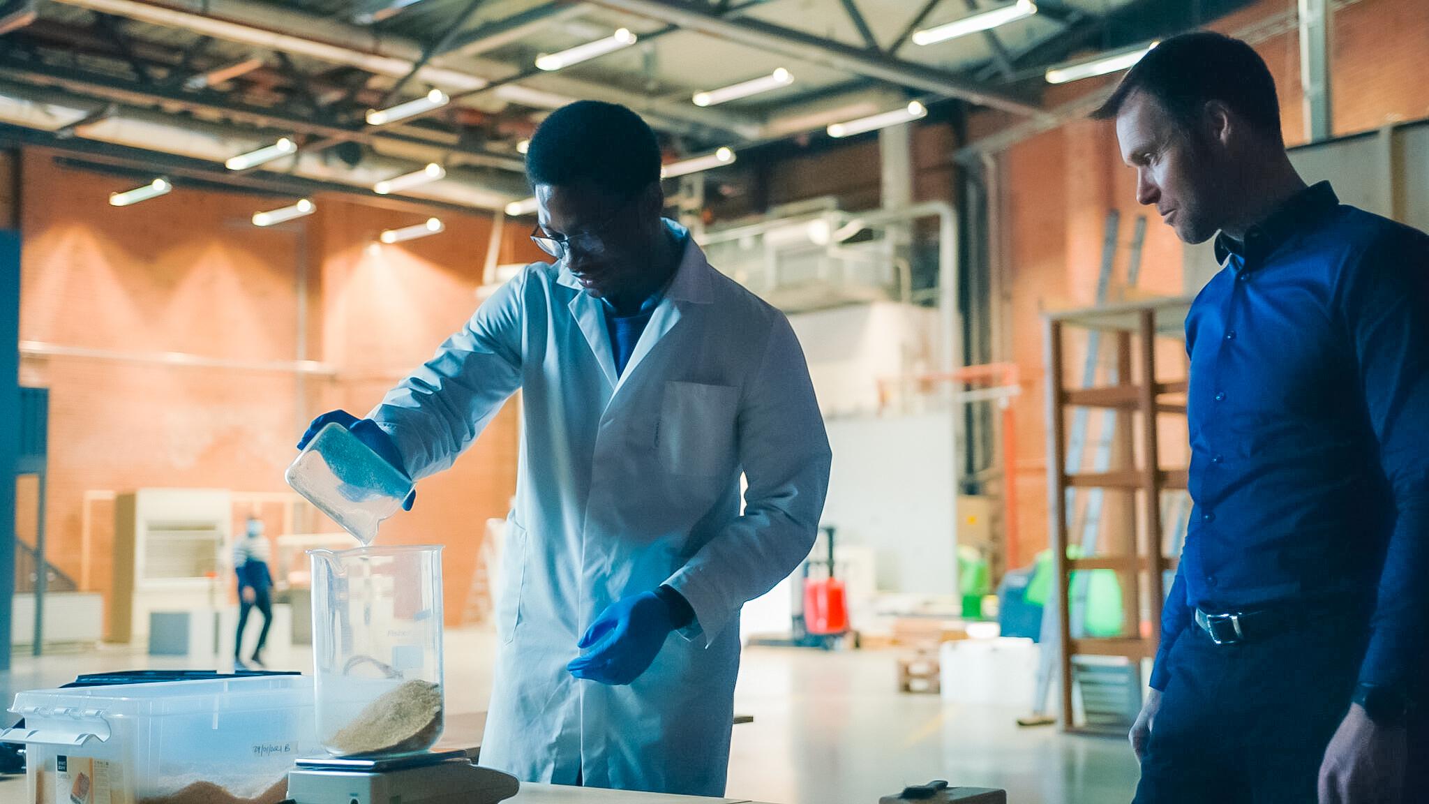 An image of a man in a lab coat pouring liquid into a jar