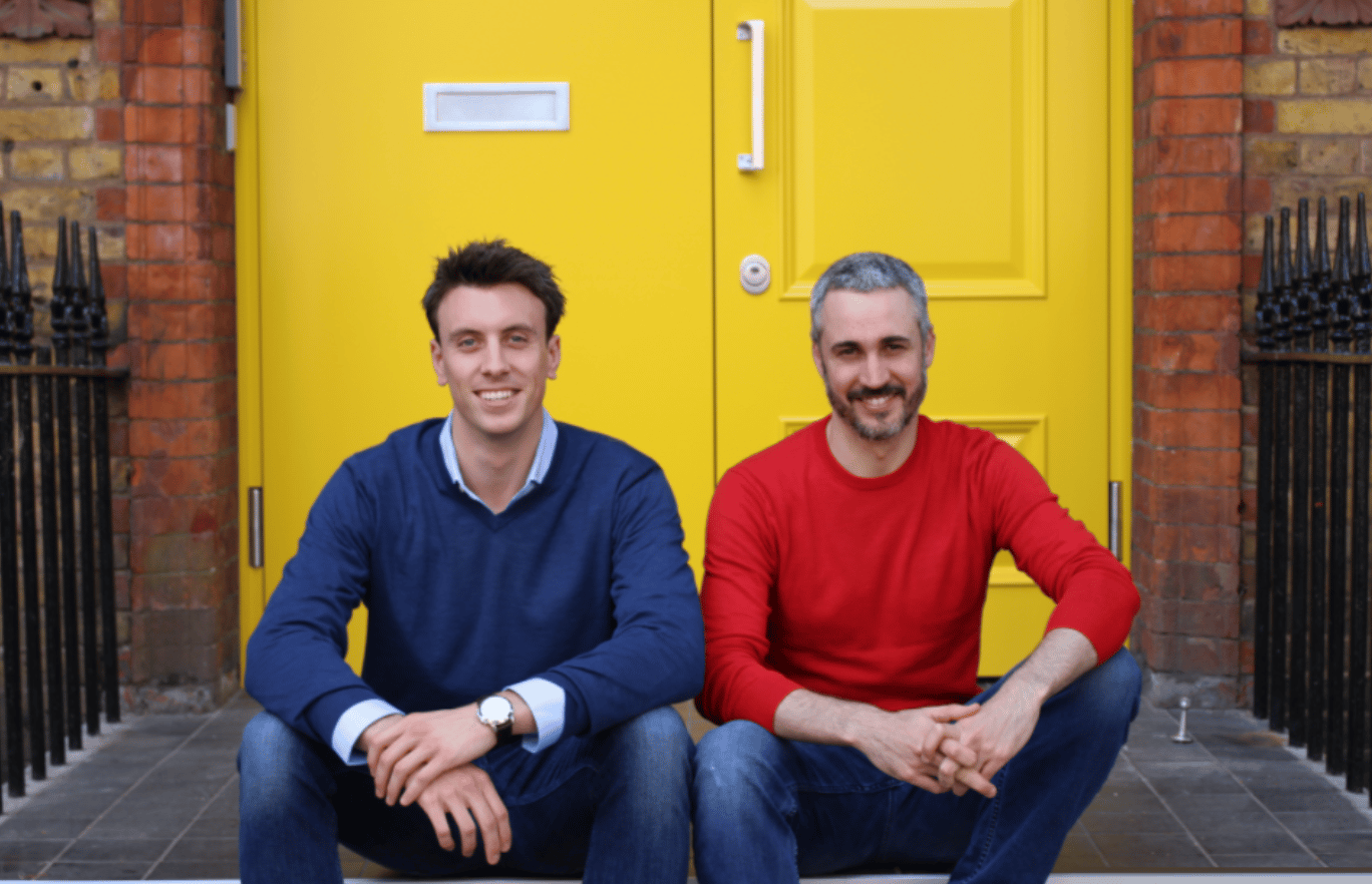 Hometree. Two cofounders sit on a doorstep in front of a bright yellow door