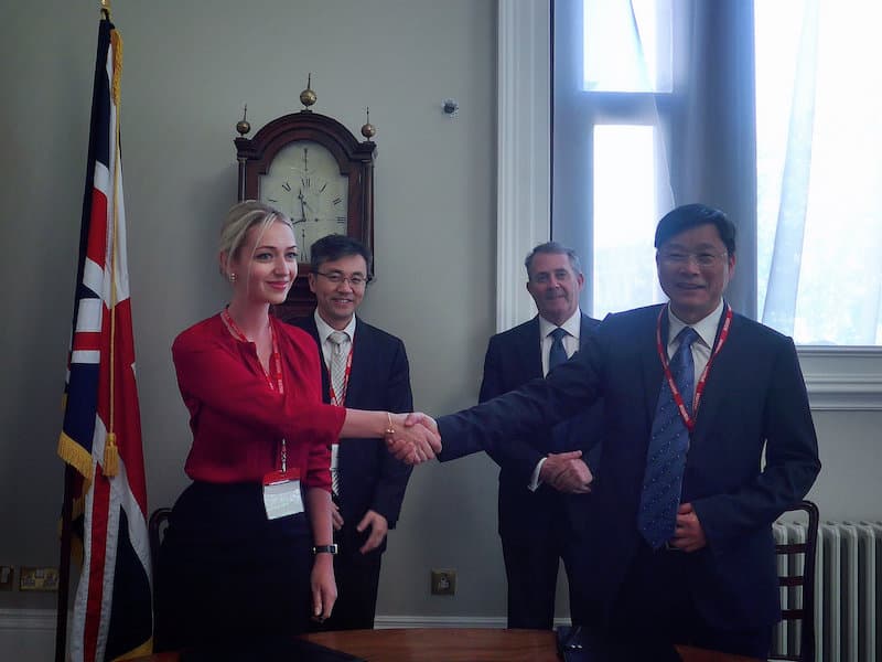 Angelica Anton signs a deal, witnessed by UK MP Liam Fox. Photo sourced from Silk's website.