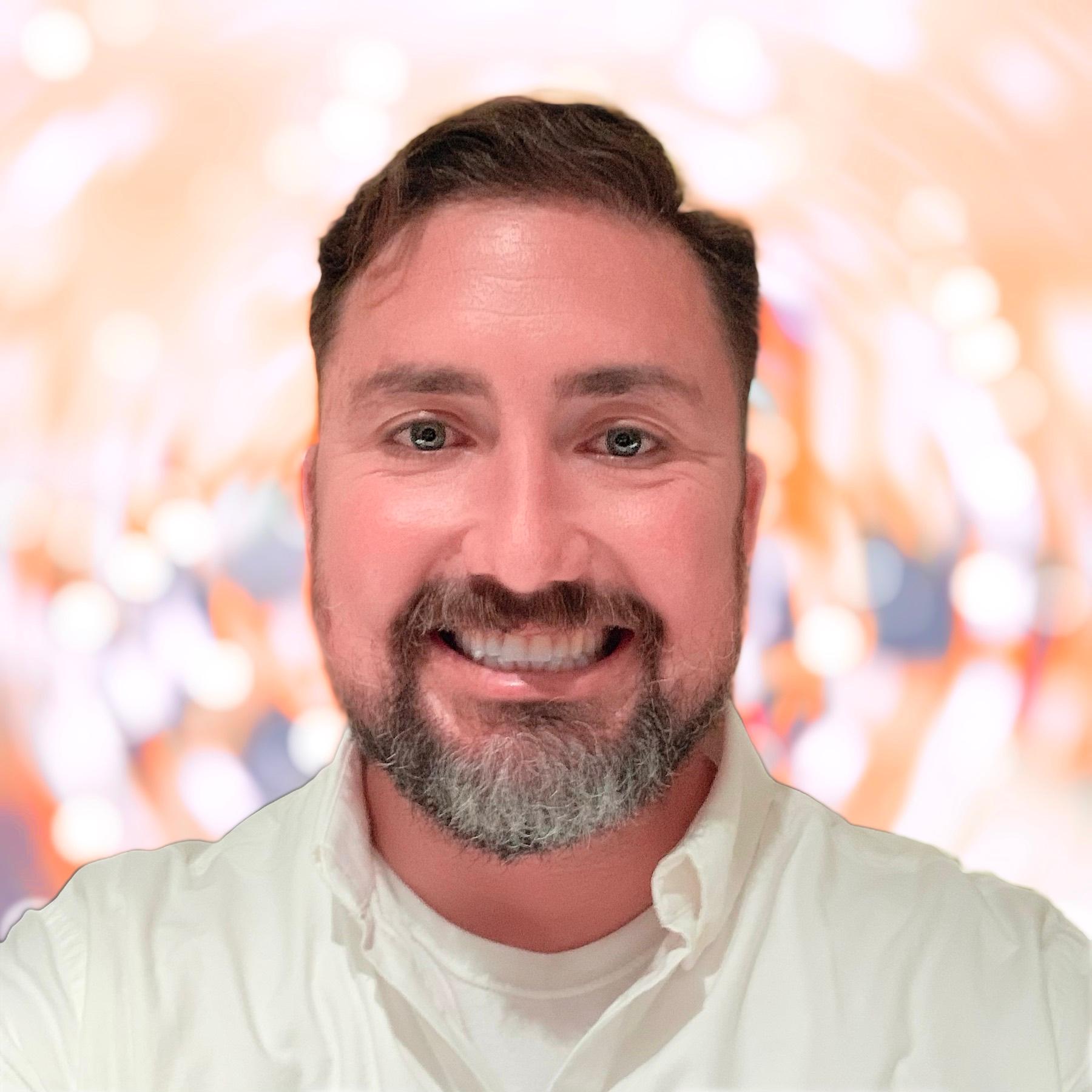 Headshot of Jeff Crusey, who is smiling against a bright blurred background