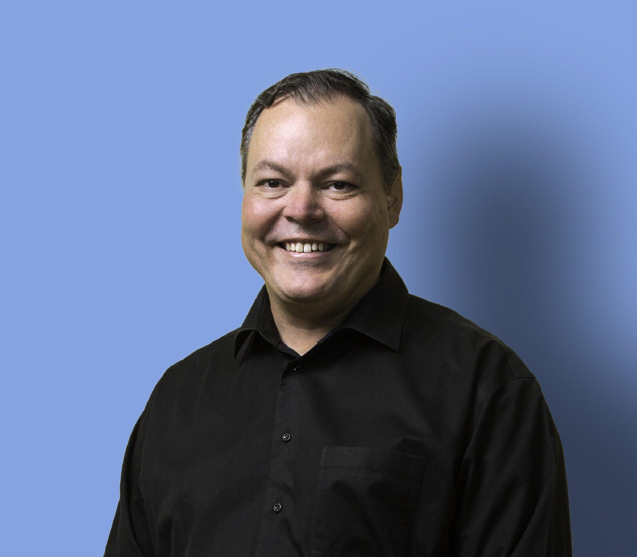 A headshot of Pirkka Palomäki against a blue background.