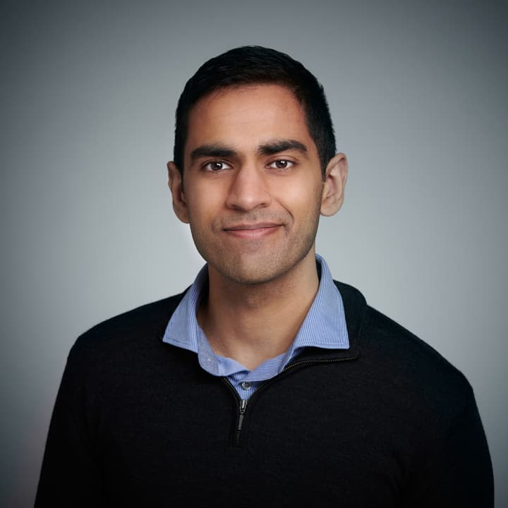 A headshot of Akash Bajwa against a grey background.
