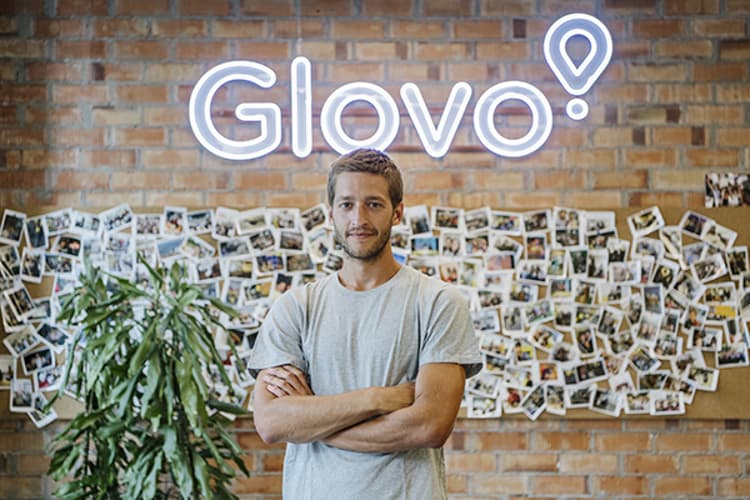 Oscar Pierre standing with his arms crossed in front of a Glovo sign