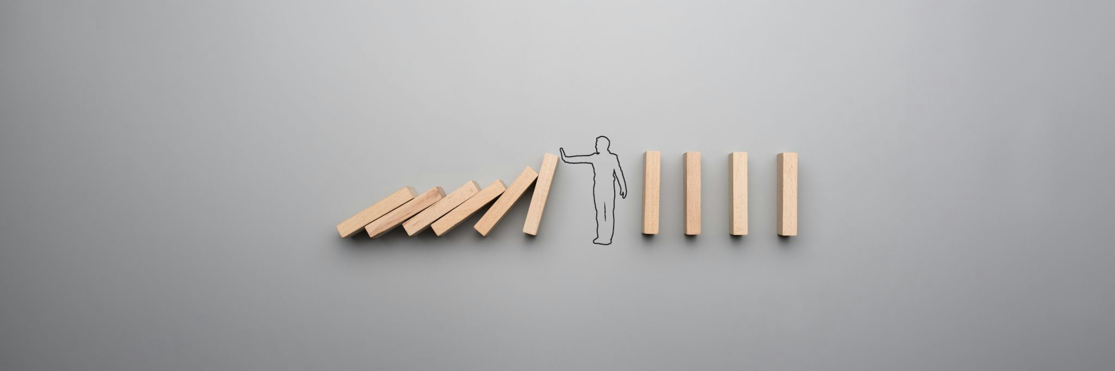 Businessman stopping the domino effect on gray background.
