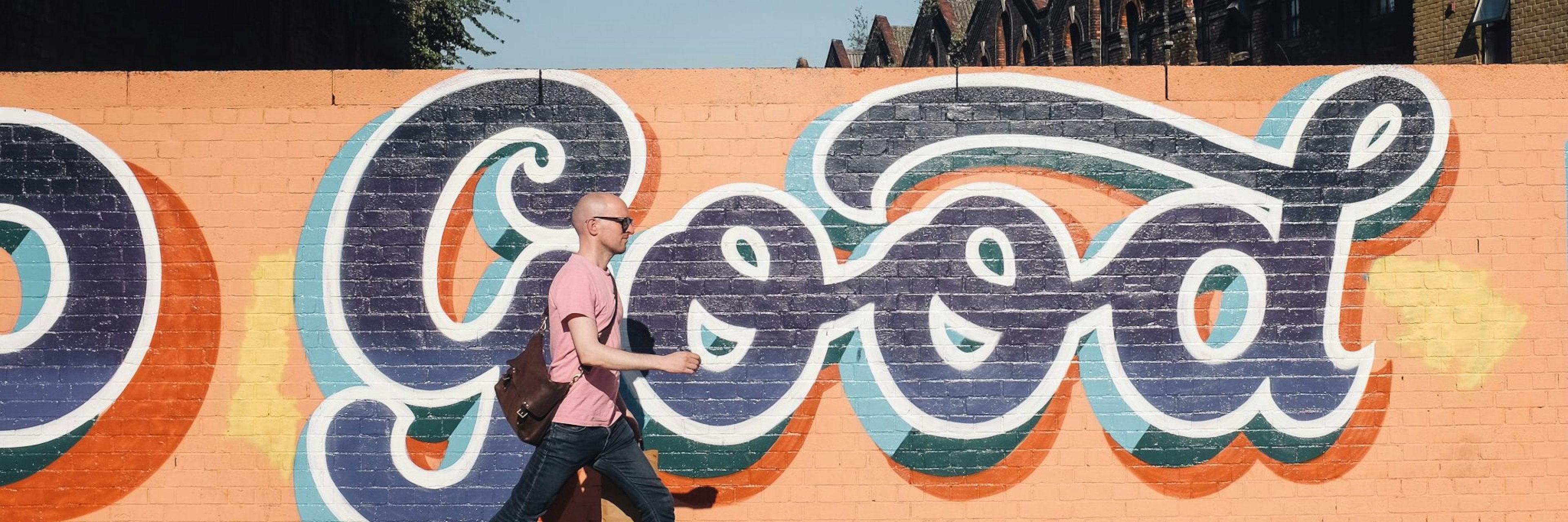 Man walking next to wall with graffiti