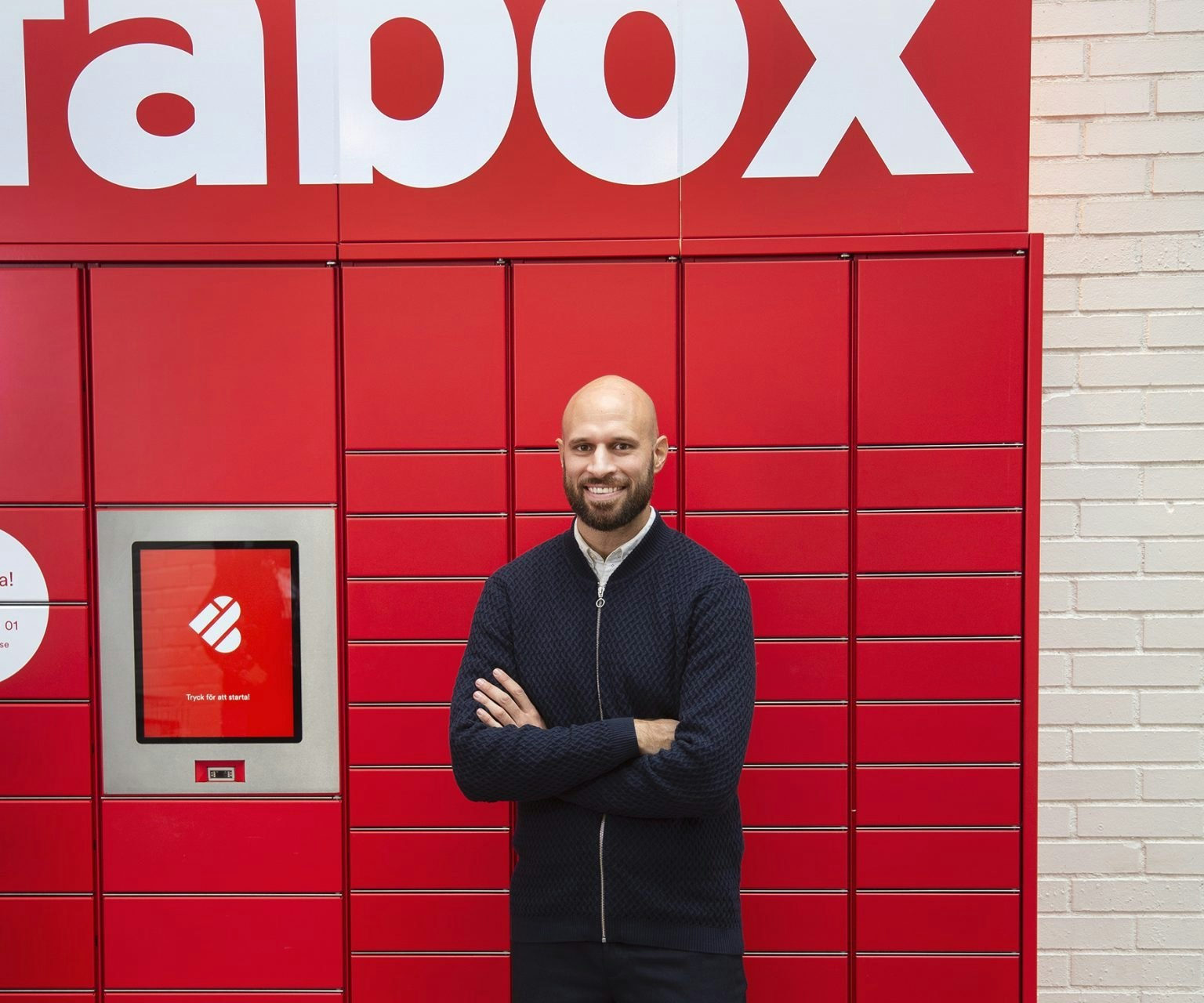Alexis Priftis stands by Instabox lockers with delivery boxes