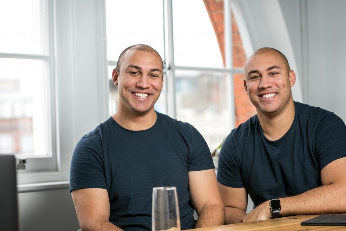 Marshmallow founders Oliver and Alexander Kent-Braham sit side by side at a table.