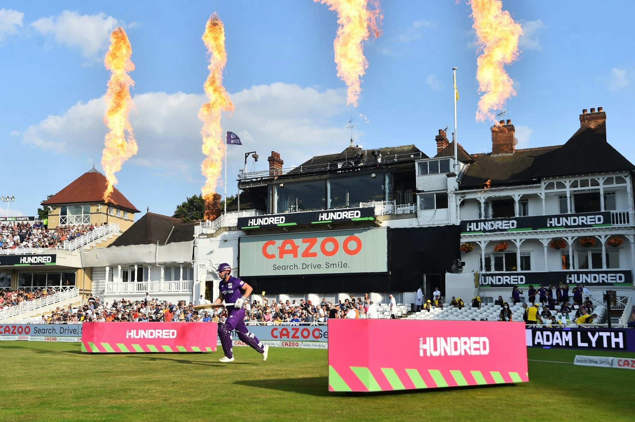 Cricketer runs onto pitch with Cazoo logo in the background.