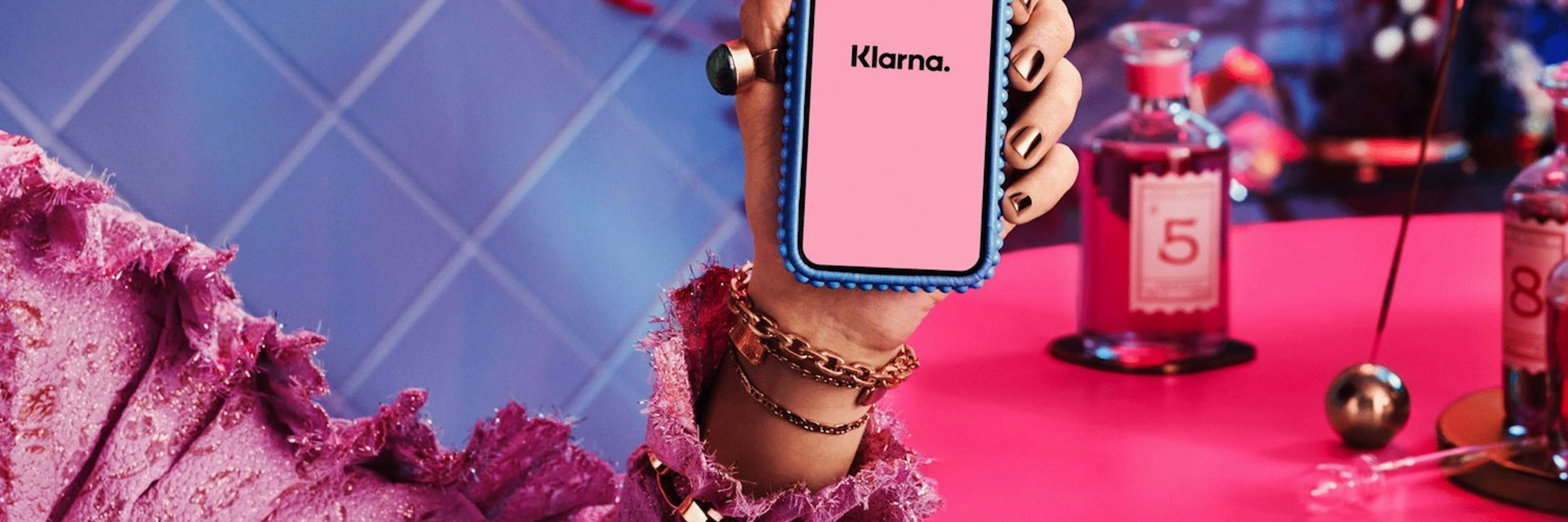 An image of someone holding a smartphone showing the Klarna app logo