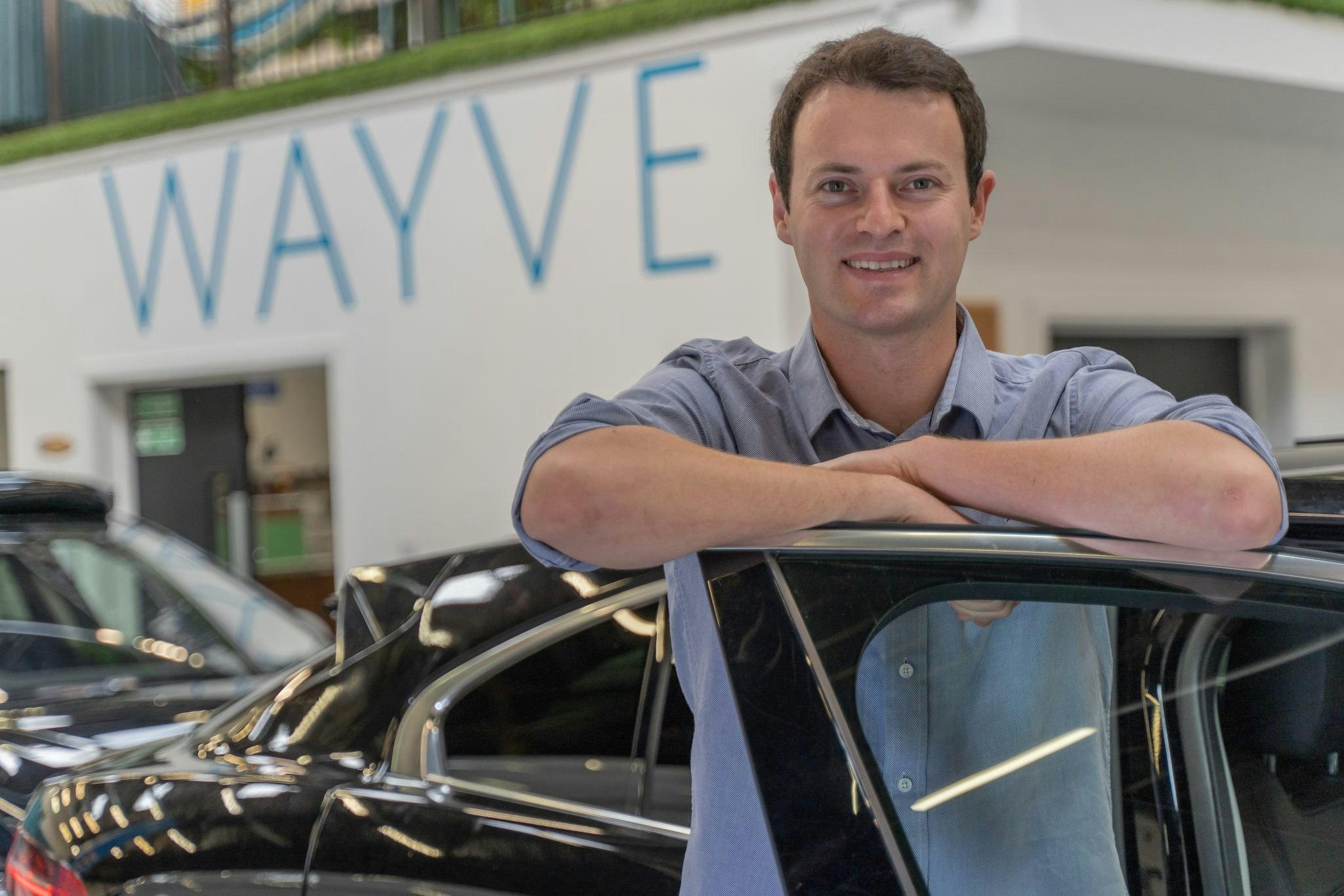 Alex Kendall CEO of Wayve leaning against at car door