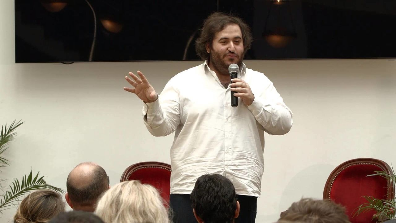A photo of Oussama Ammar speaking at a conference