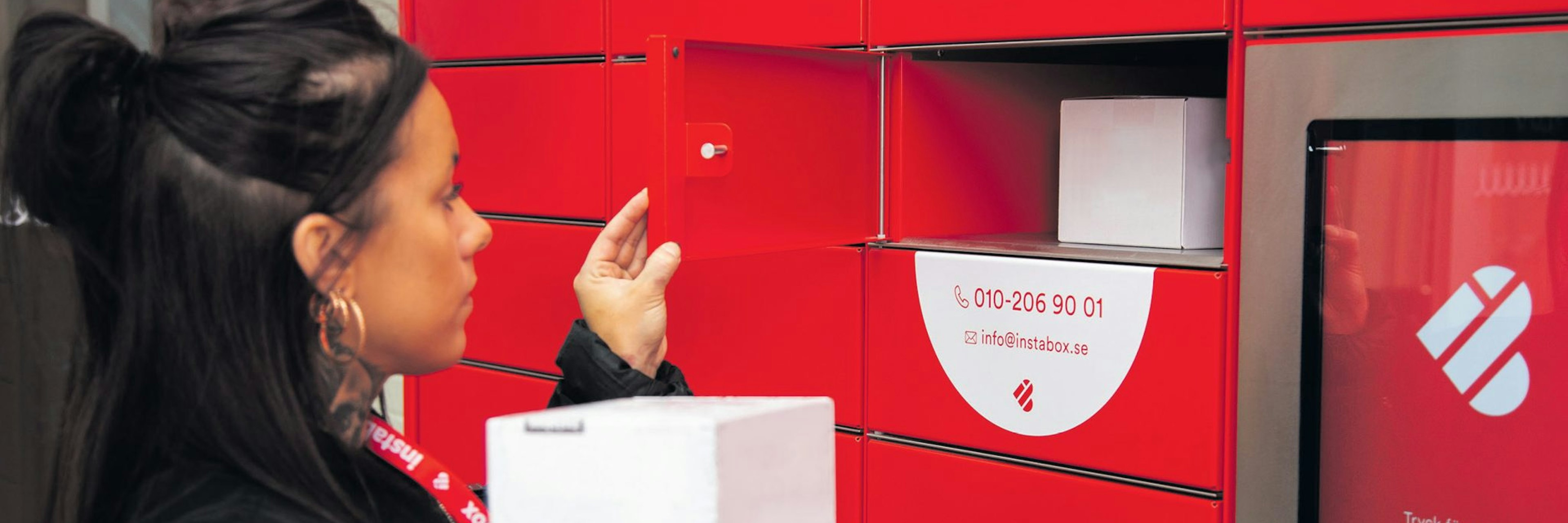 A woman collects some parcels from a bright red Instabox parcel locker
