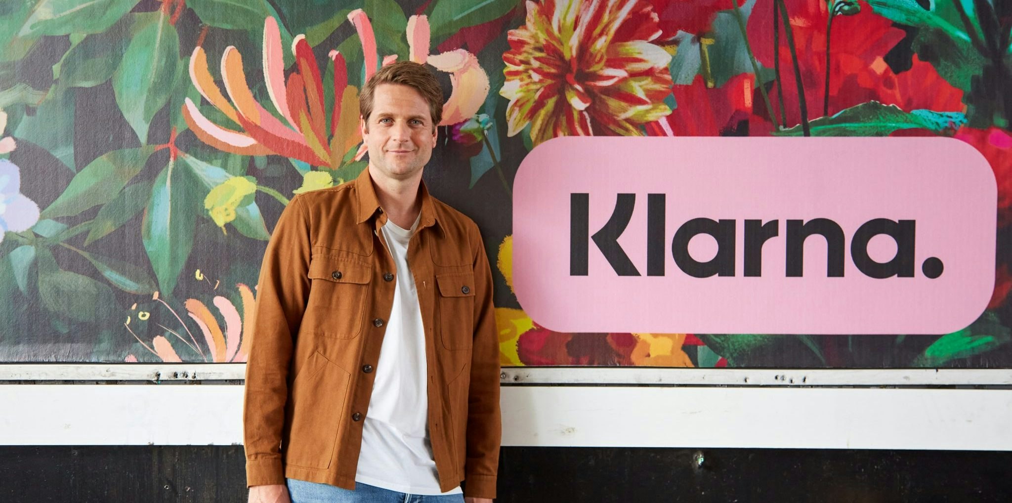 An image of Sebastian Siemiatkowski, CEO of Klarna, standing next to a Klarna sign.