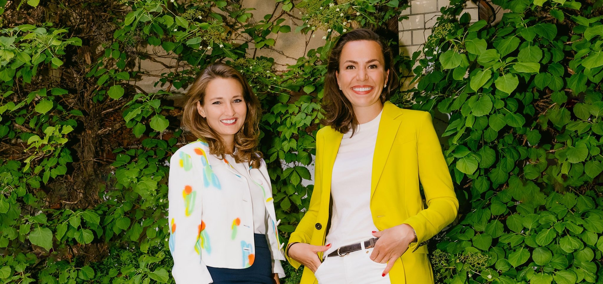 Two women standing in front of greenery. They are the cofounders of Topi