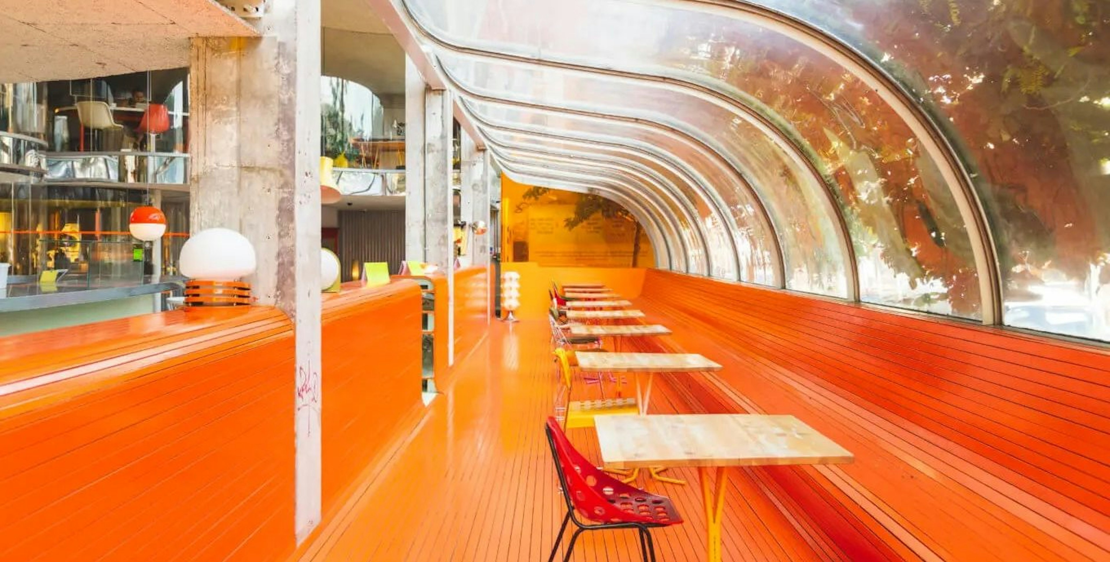 The curved see-through roof and bright orange seating area of Second Home Spitalfields' cafe