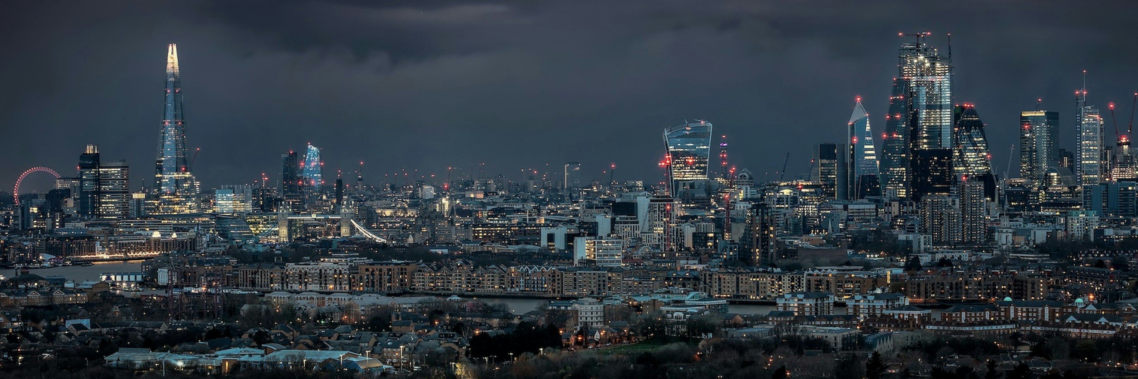 City skyline of London at night under a dark cloudy sky
