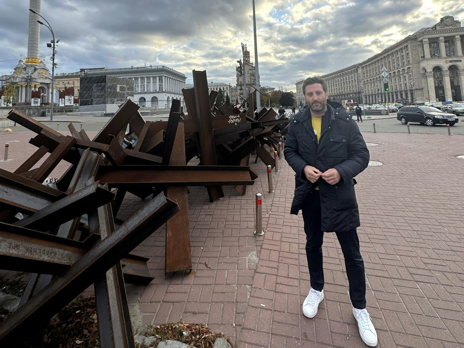 An image of Daniel Korski in Ukraine, standing in a city square next to some shoulder-high tank traps
