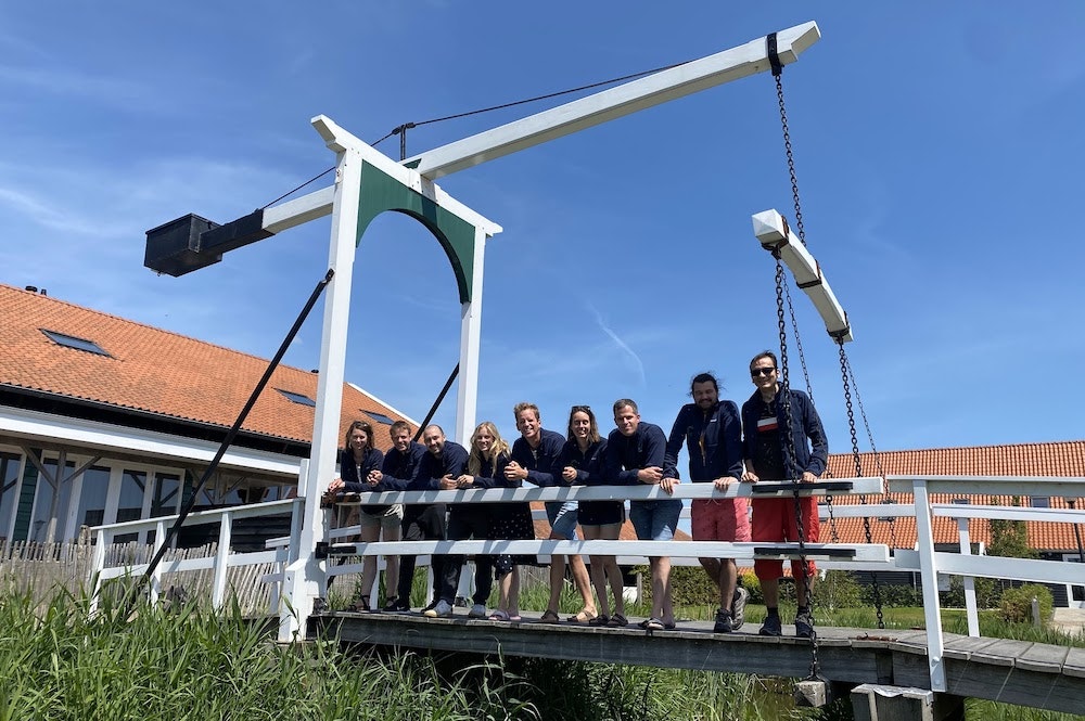 A landscape image of Cradle's team in matching blue sweaters standing on a wooden bridge