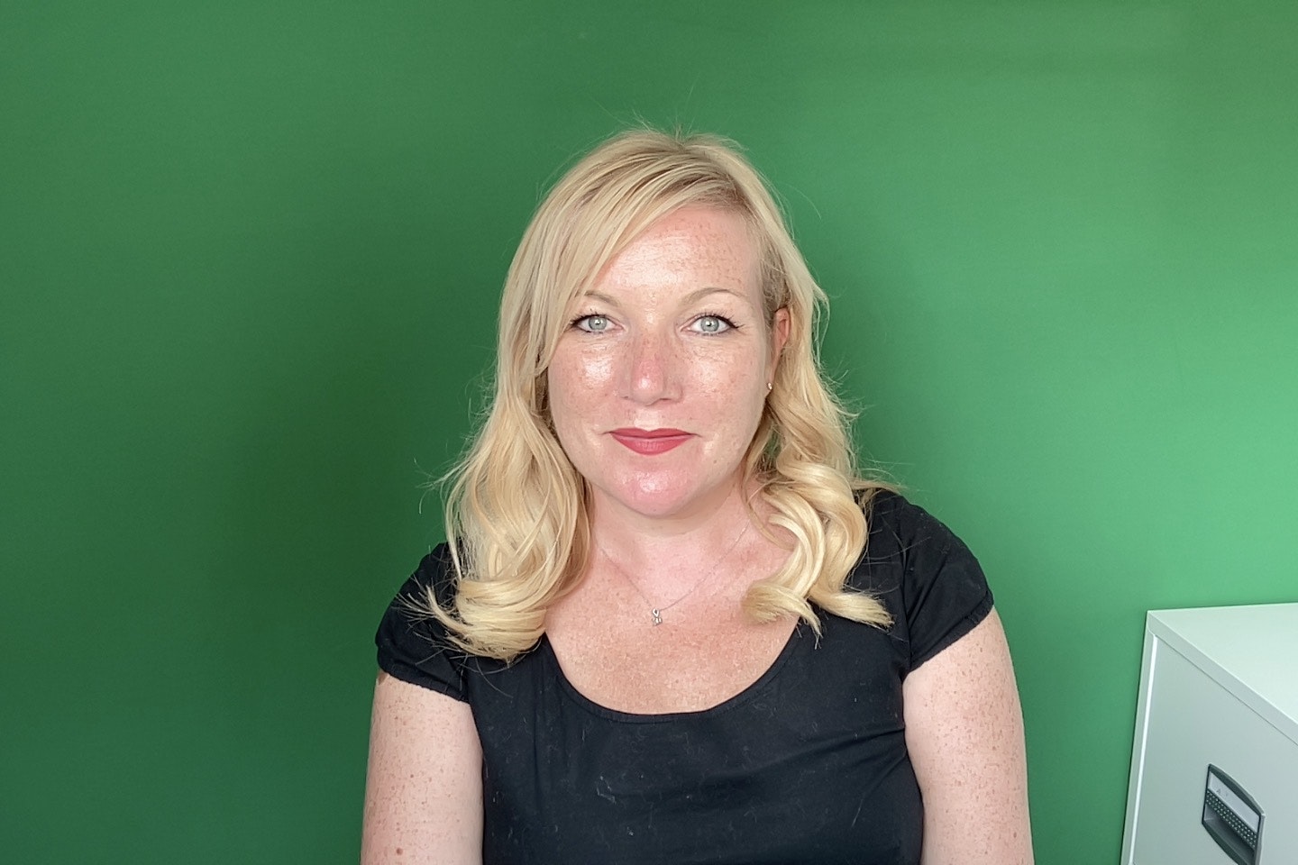 A photo of Kim-Adele Randall, an alternative business coach, in front of a green screen