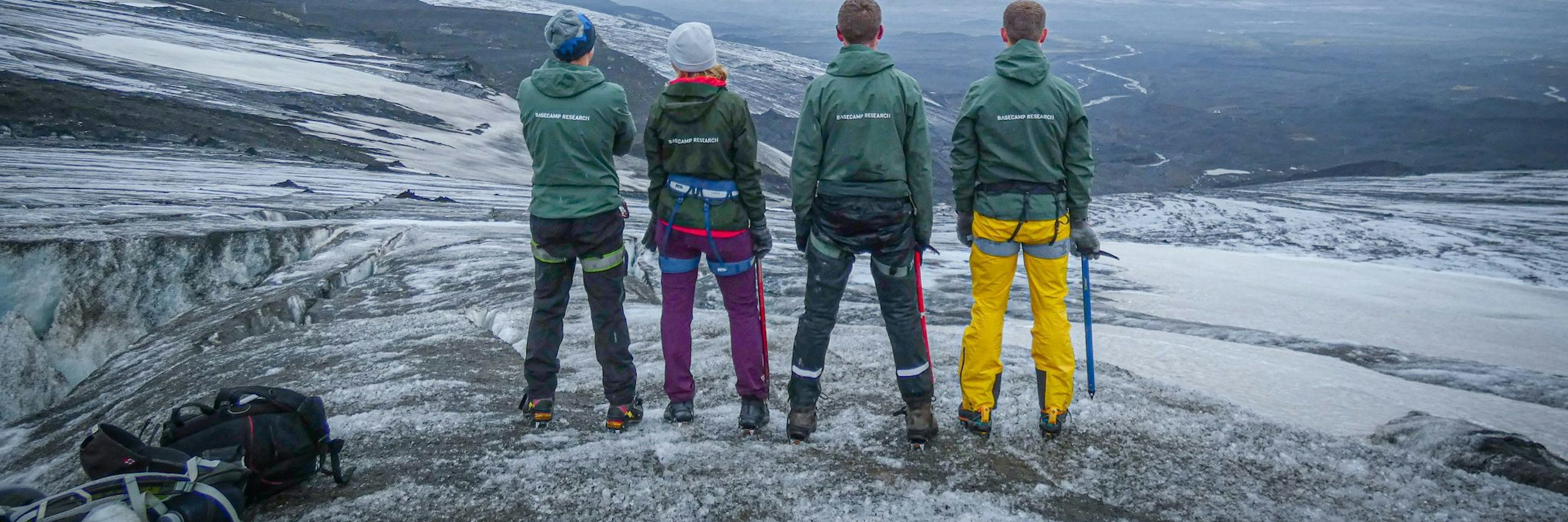 An image of the four members of the Basecamp team, facing away from the camera towards a snowy landscape