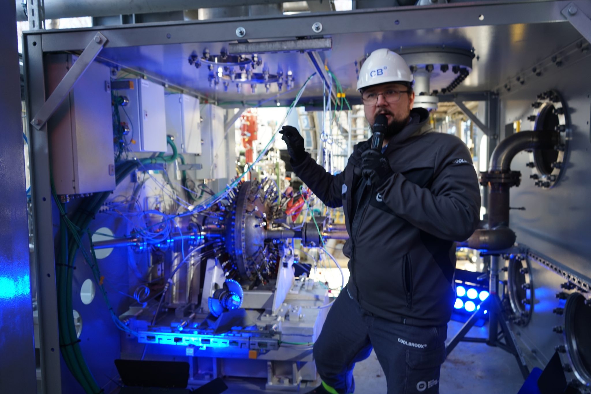 A man in a hard hat stands next to an industrial contraption