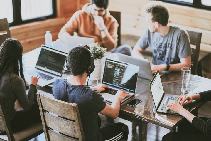 People sitting around a table, working on laptops