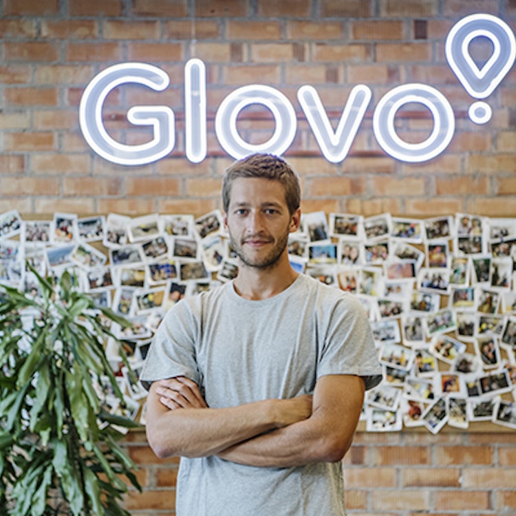 Oscar Pierre standing with his arms crossed in front of a Glovo sign