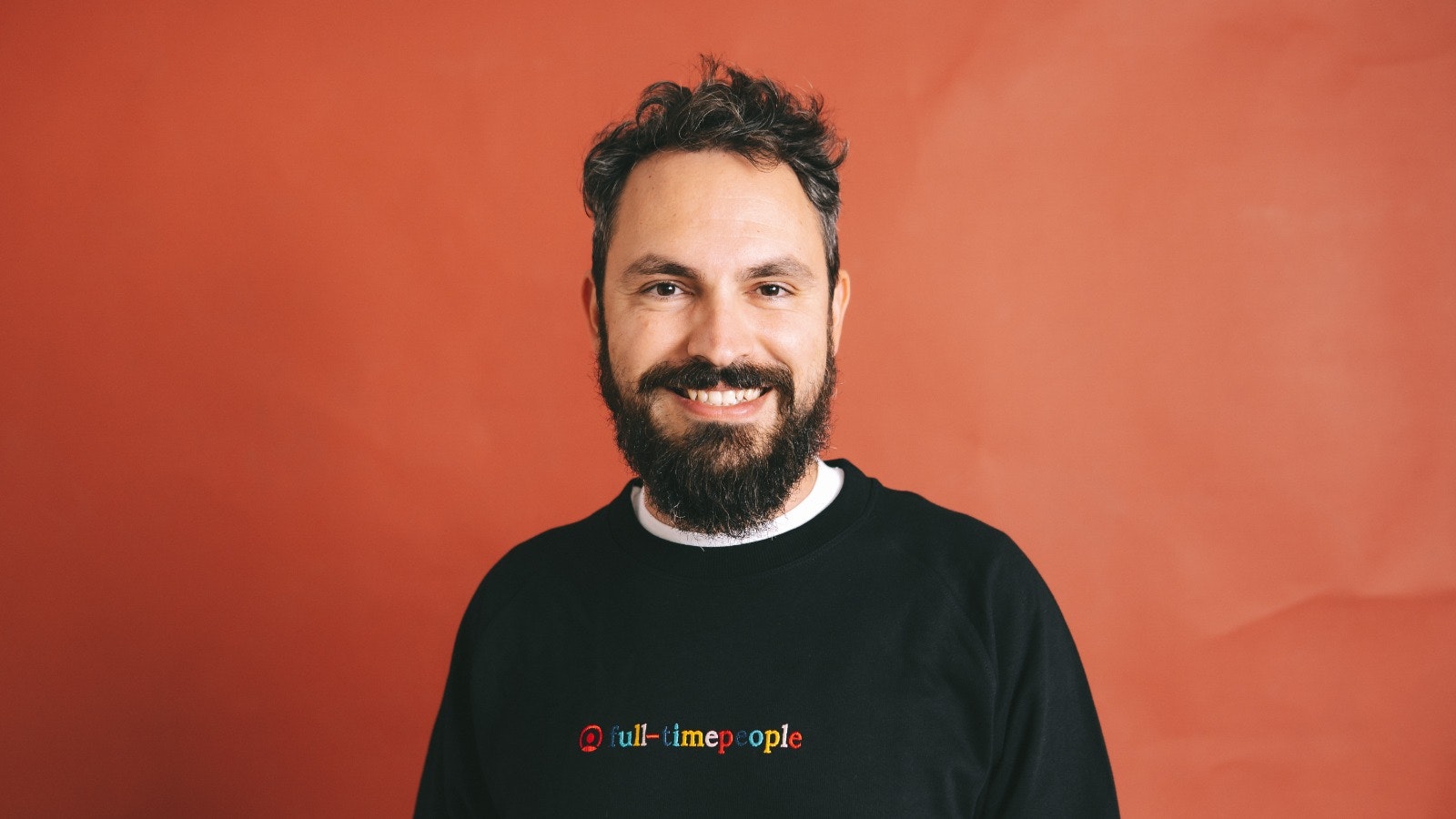 A headshot of Jordi Romero against an orange background