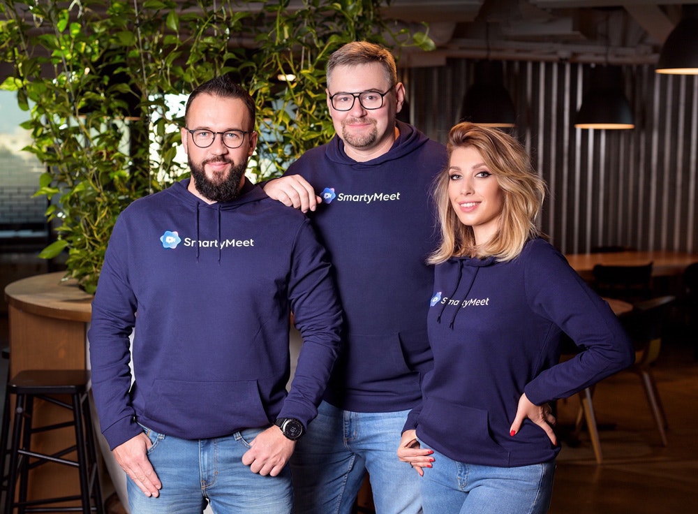 Three people — two men and a woman — in purple hoodies