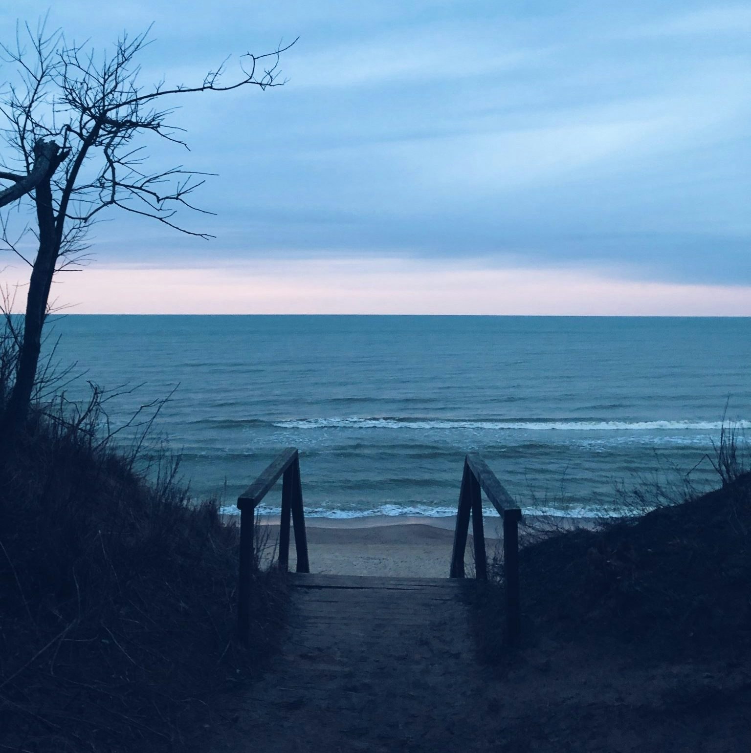 An image of some wooden steps leading down to a beach under a cloudy sky