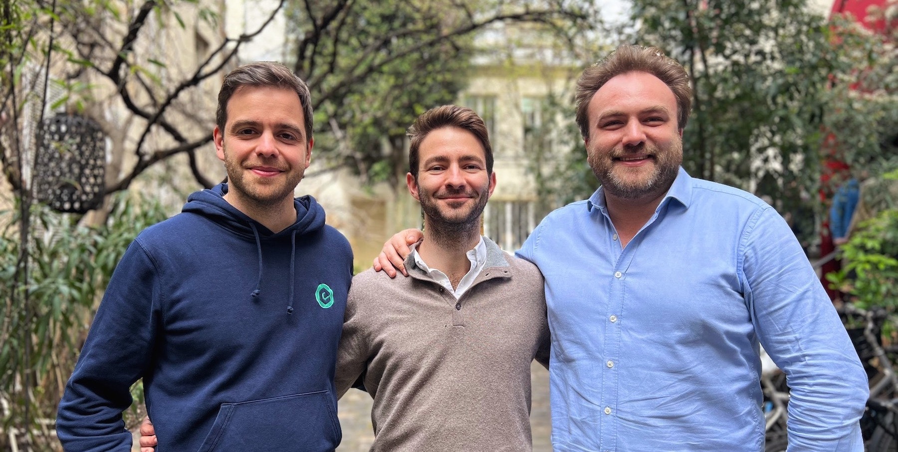 The founders of Roundtable, three men smiling at the camera with greenery in the background