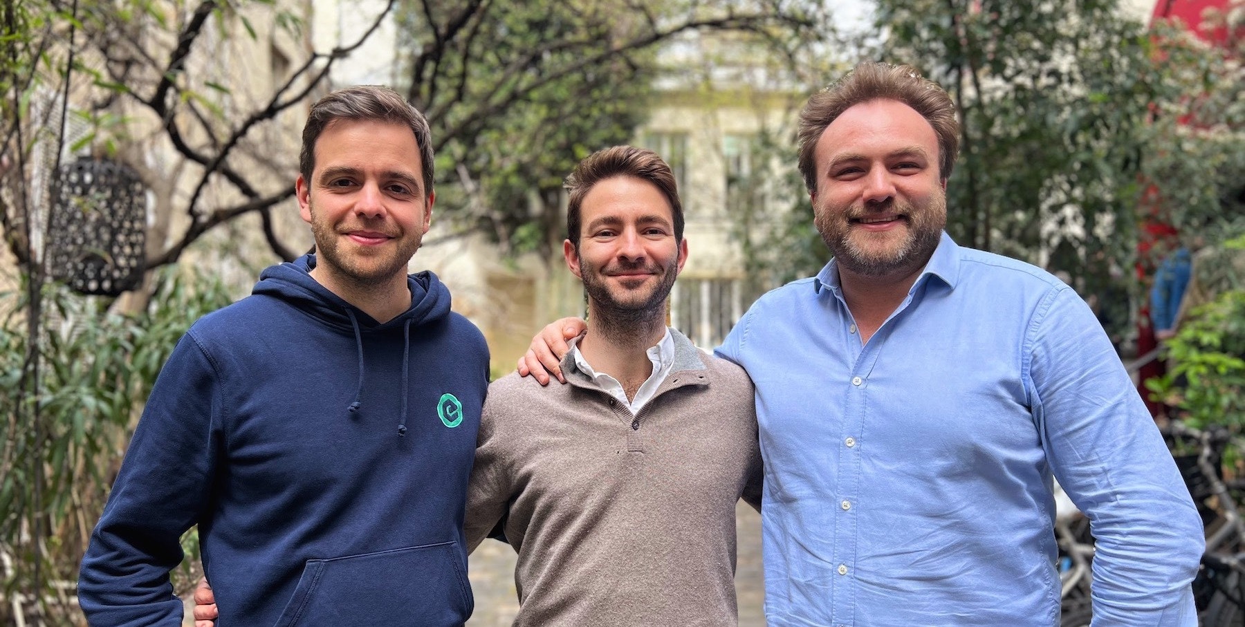 The founders of Roundtable, three men smiling at the camera with greenery in the background