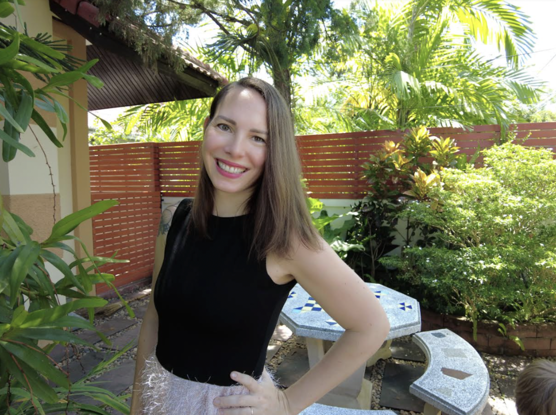 An image of Ella Heart posing in the garden of a tropical house