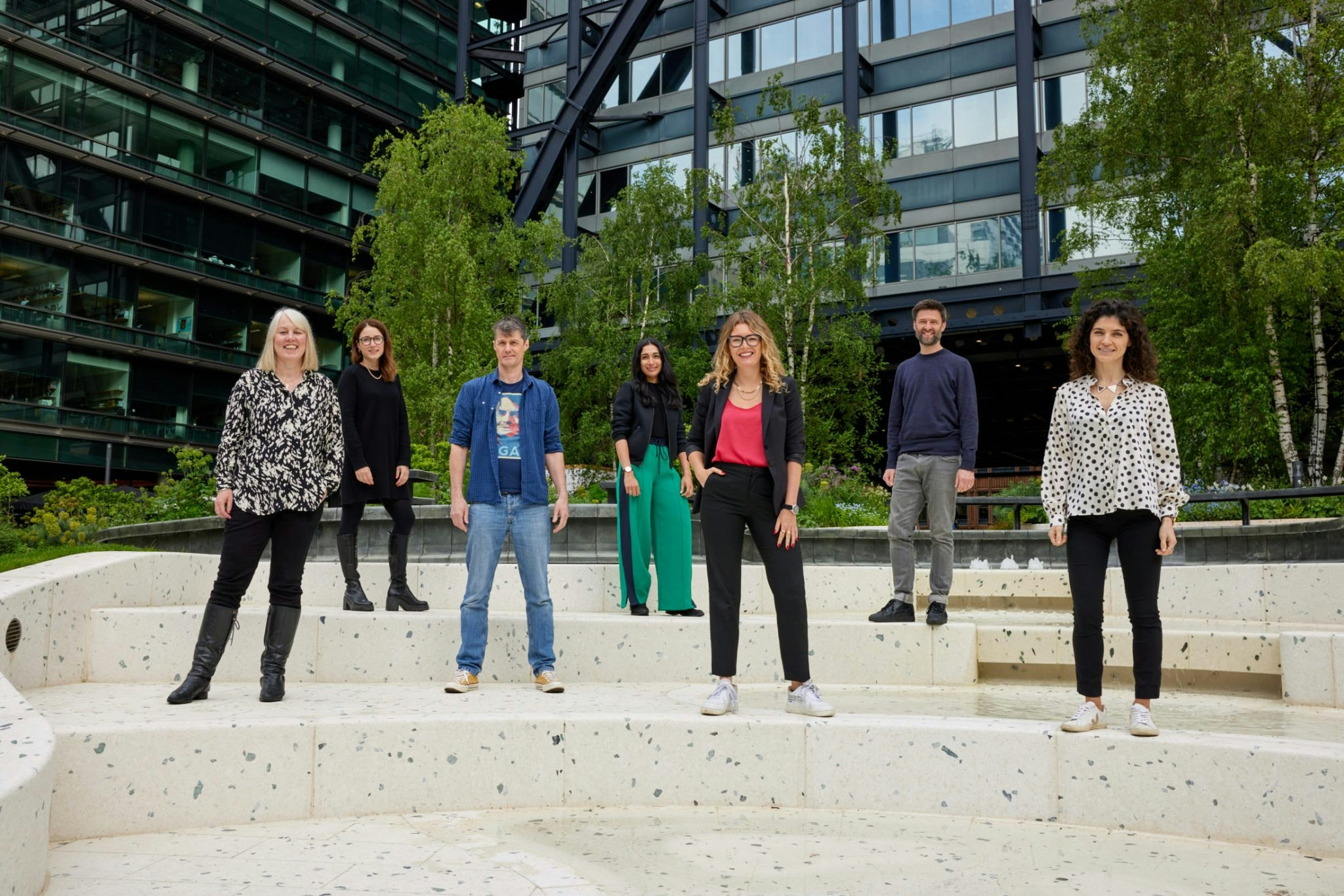 A photo of the seven team members stood in front of a black office building