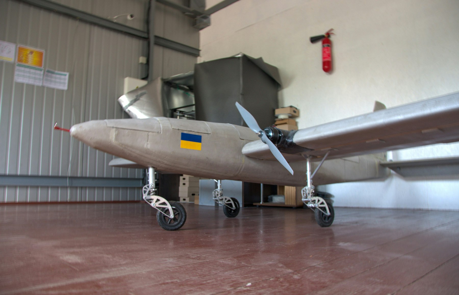 A photograph of an AirLogix drone, with a Ukrainian flag painted on its side, in a hangar