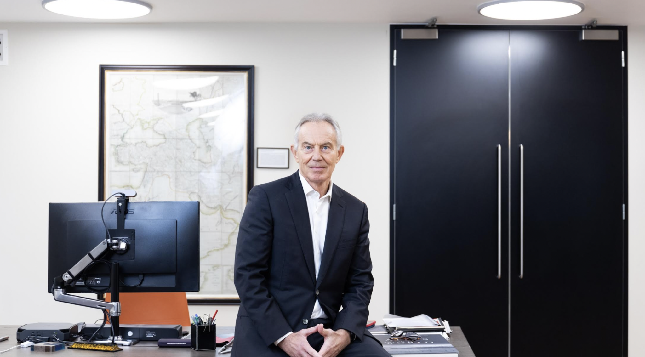 Former UK Prime Minister Tony Blair perched on a desk
