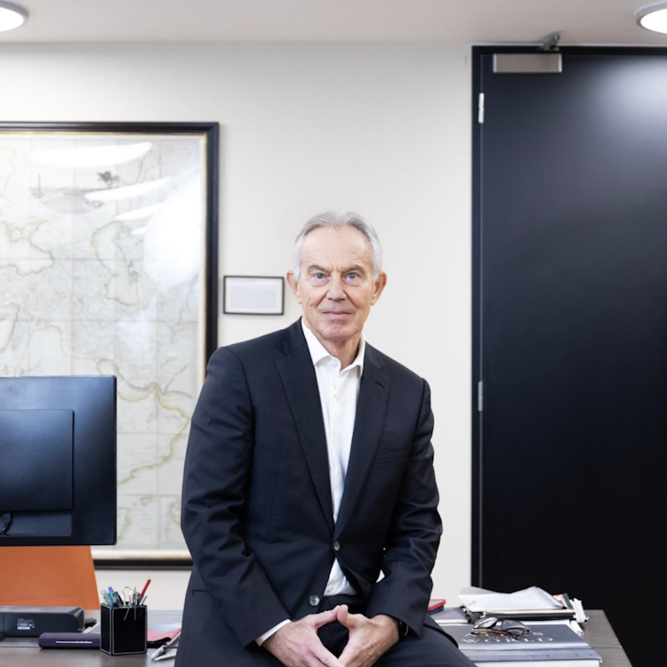 Former UK Prime Minister Tony Blair perched on a desk