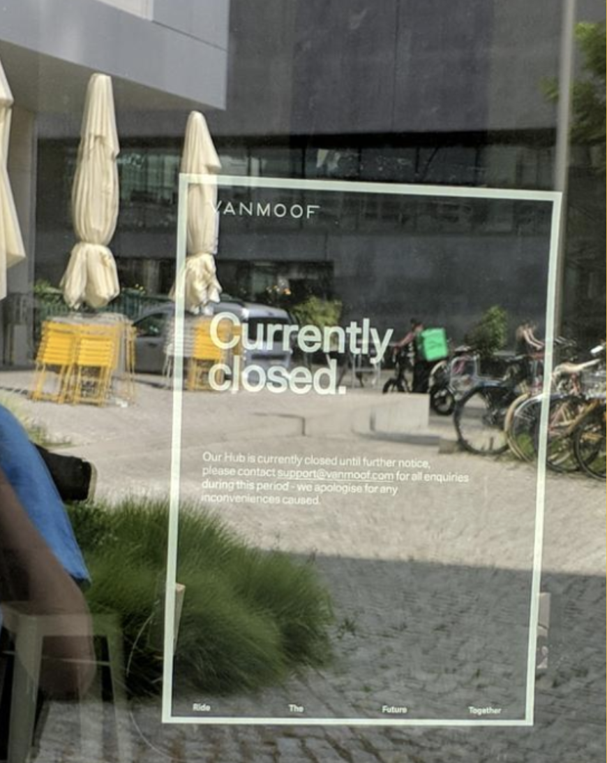 An image of the front of a VanMoof store with a sign saying &quot;currently closed&quot;