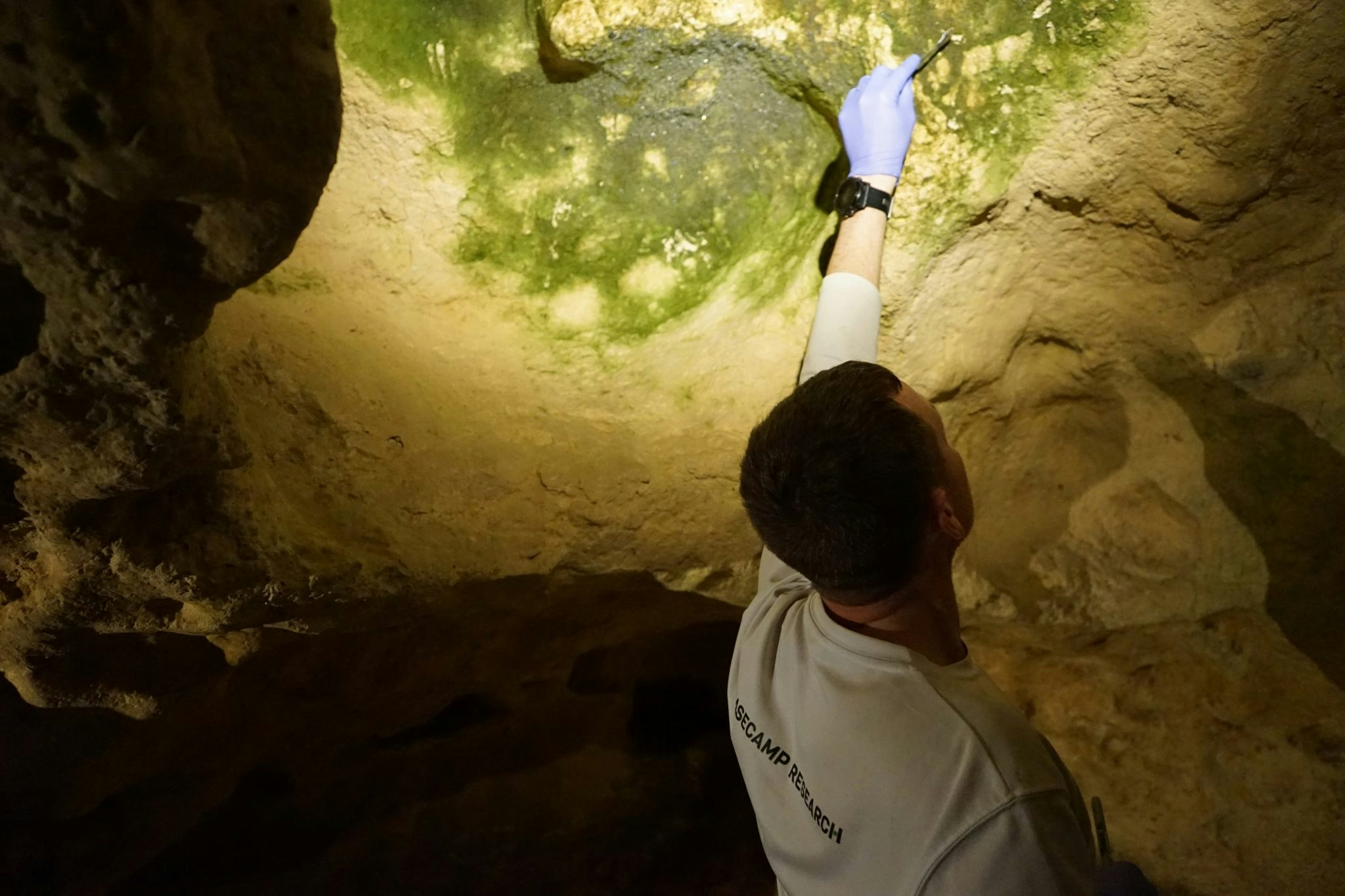 Basecamp's Clark scrapes a substance off a cave ceiling.