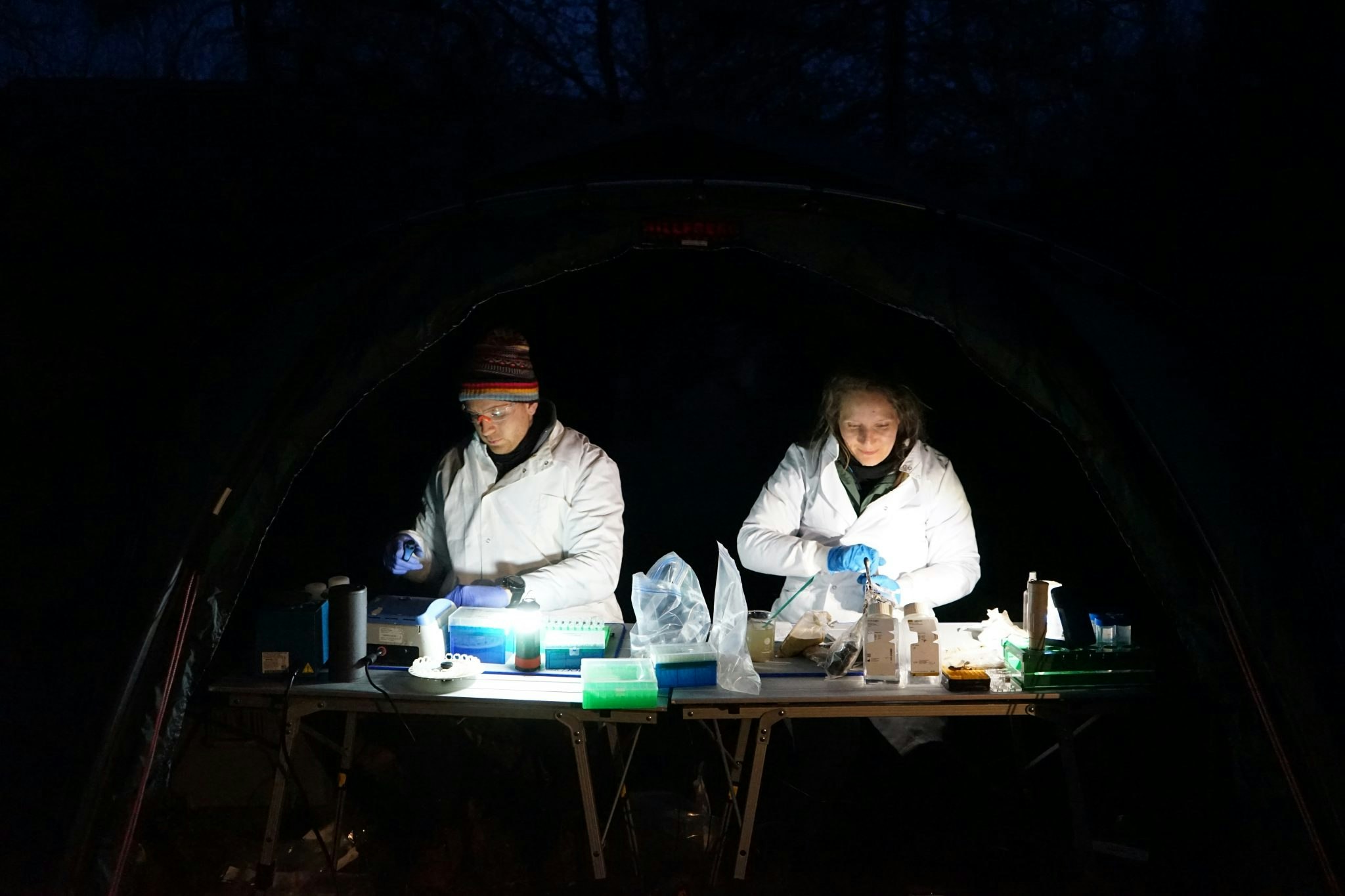 The Basecamp team working under lights in the darkness outside.