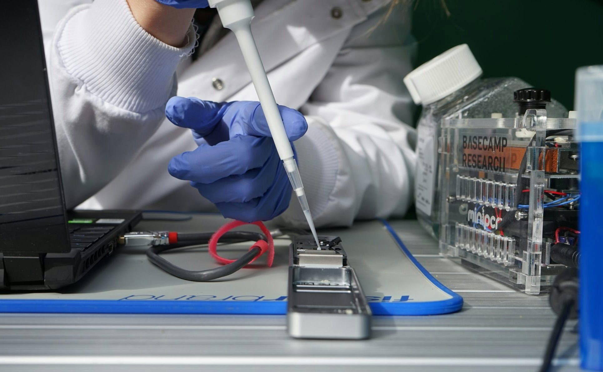 A close up of a scientist from Basecamp conducting an experiment with lab equipment.