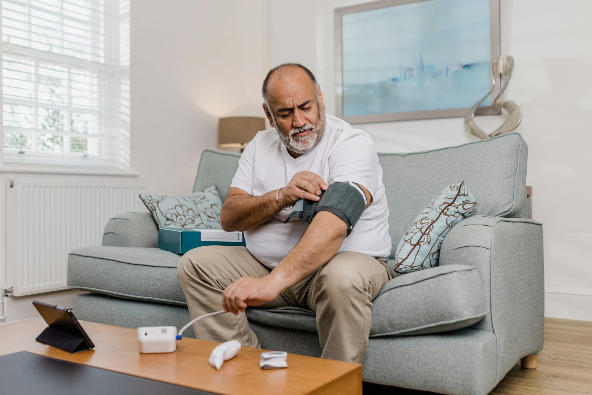 A photograph of an elderly man taking a blood pressure test at home