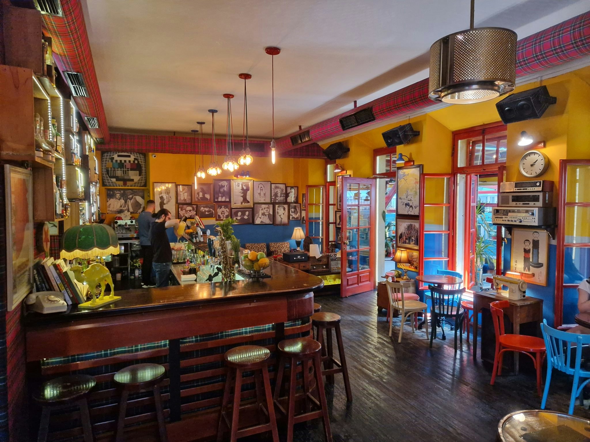 A colourful bar with multicoloured chairs, yellow walls and a wooden bar area.