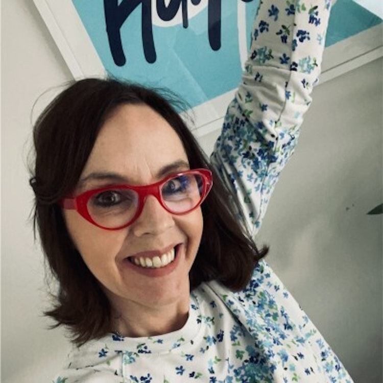 A selfie of Vanessa O’Mahony with one arm raised. She is wearing red glasses and is smiling at the camera