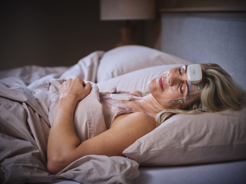 Onera's at-home PSG test in use, showing a woman asleep wearing the device.
