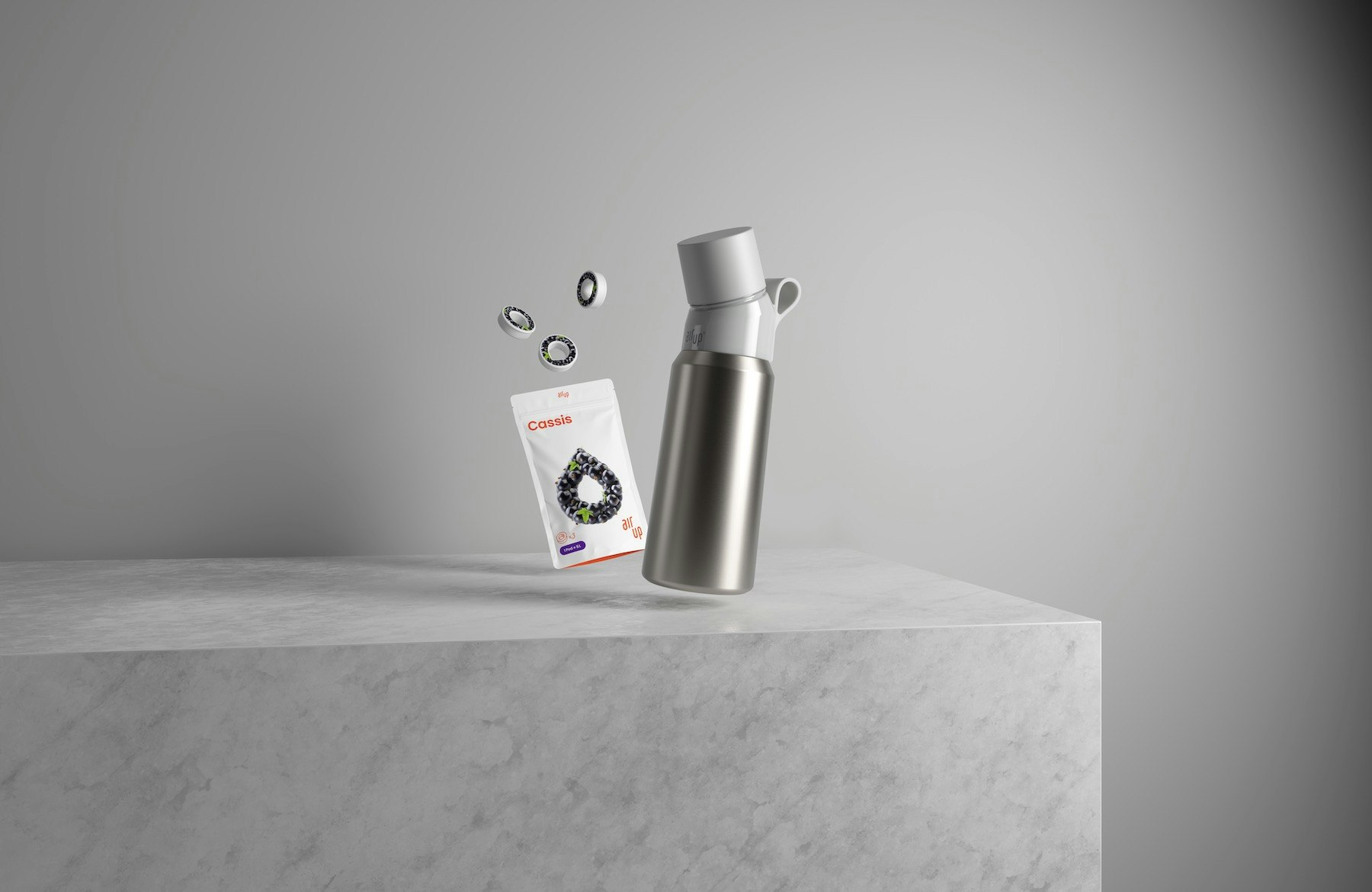 A photo of a black and silver air up bottle and pods on a grey table and background 
