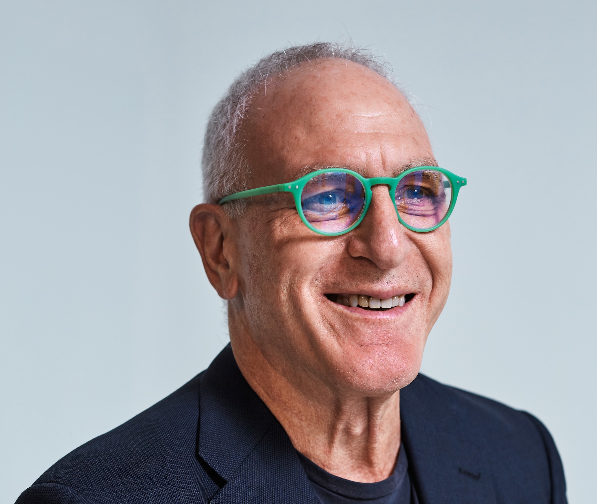 A headshot of Rob Bier who is smiling and wearing green glasses and a black tshirt.
